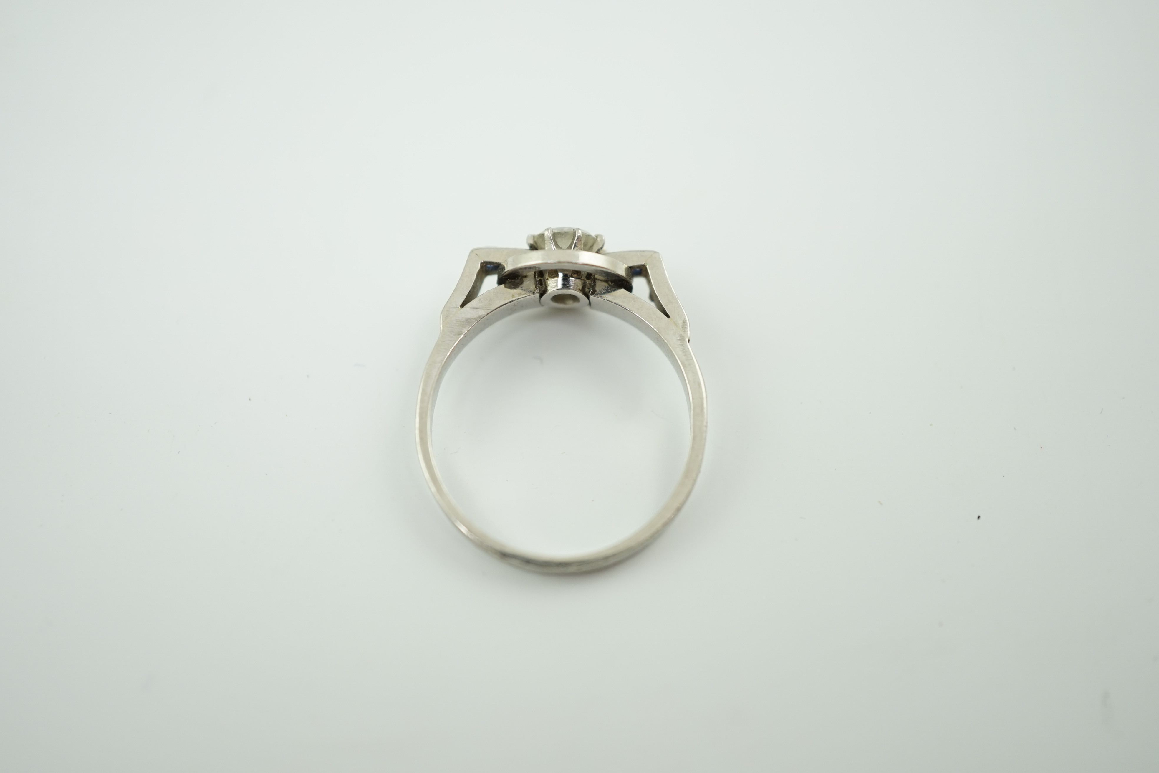 A platinum and single stone diamond set target ring, with four stone square cut sapphire set shoulders